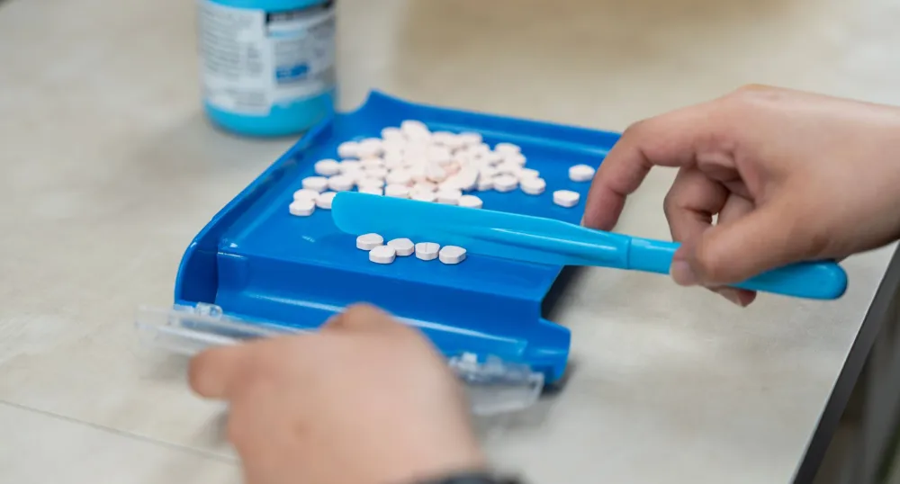 Des comprimés blancs placés sur une plateforme bleue pour être comptés.