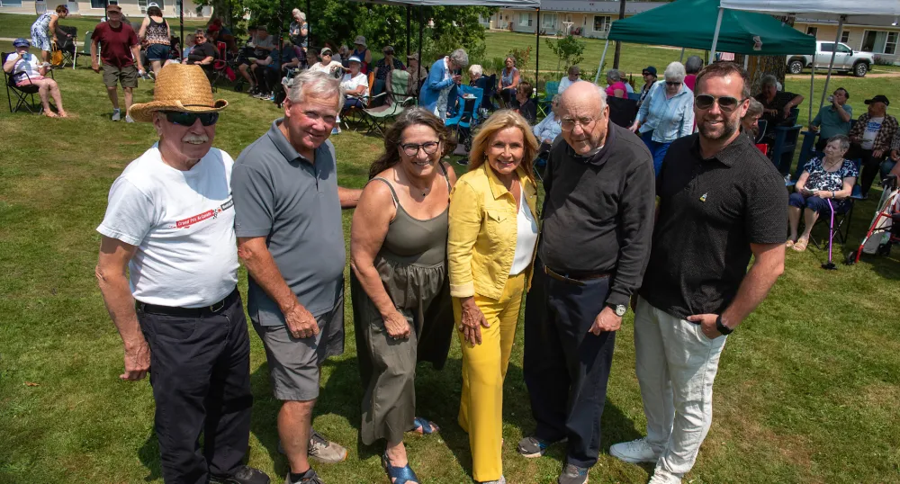 Five people stand together outside during a sunny day.