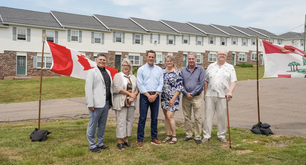 Six people standing in front of housing units 