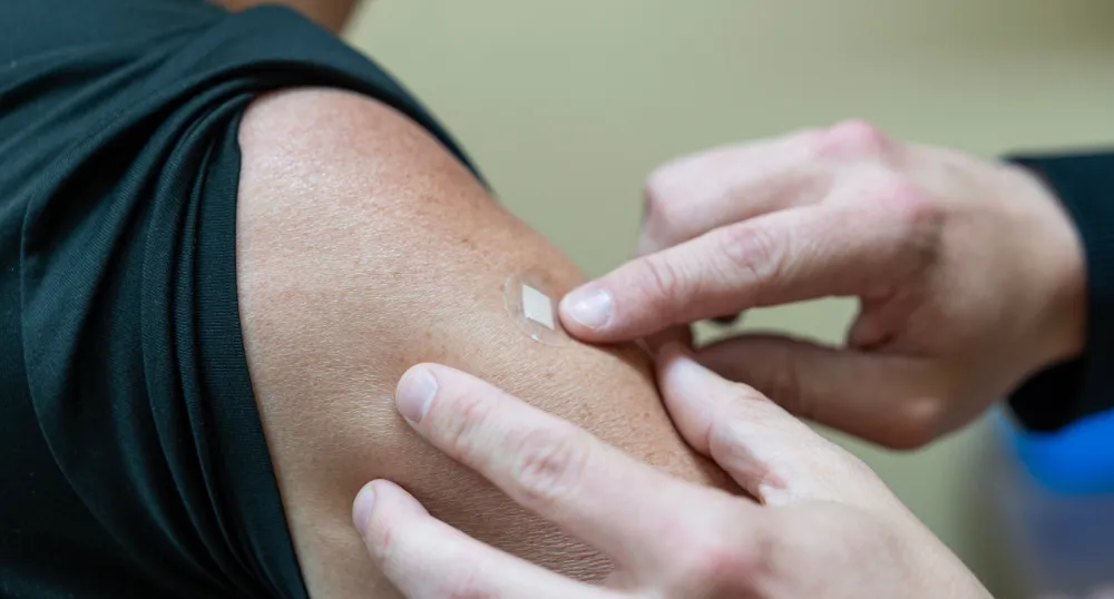 An arm with a small bandage over a recent vaccination site.
