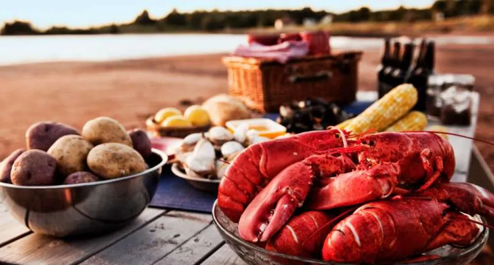 Rustic table set with PEI oysters, cooked lobster, mussels, lemon and lime