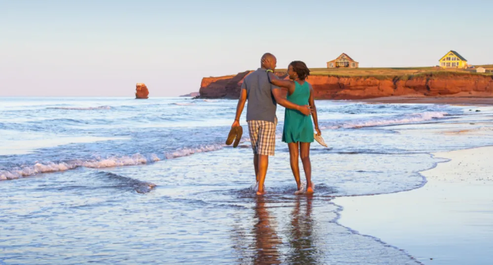 Couple strolls along red sand beach on Prince Edward Island