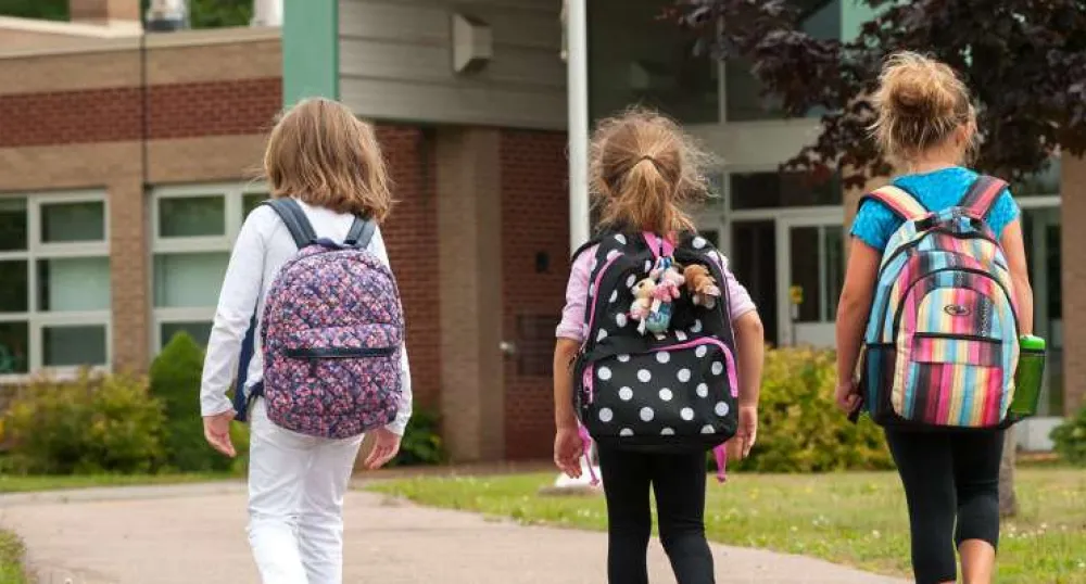 Back to school in PEI Three elementary school children walking to front door of PEI school
