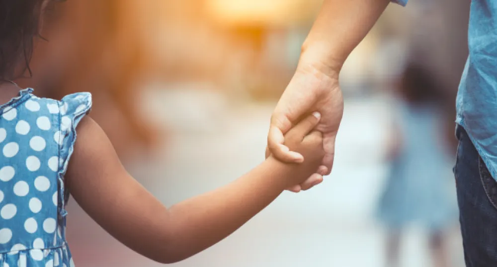 child and adult holding hands