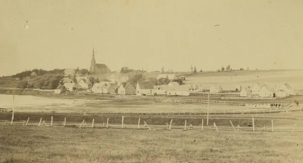 Community of St. Peters, Prince Edward Island, ca. 1870-1880. A wooden bridge across the St. Peters Bay can be seen, as well as a church in the background. Several other buildings and structures are also visible. A small boat is in the lower left corner.