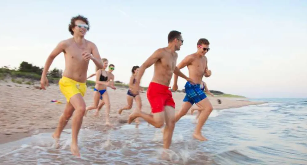 Group of youth run into the water at Basin Head beach