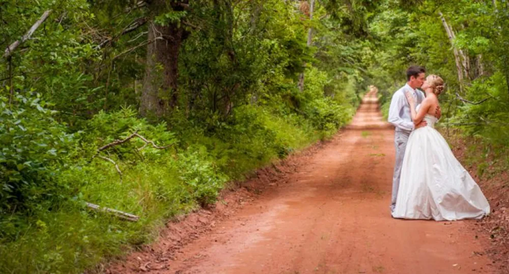 Bride and groom on red dirt road in PEI