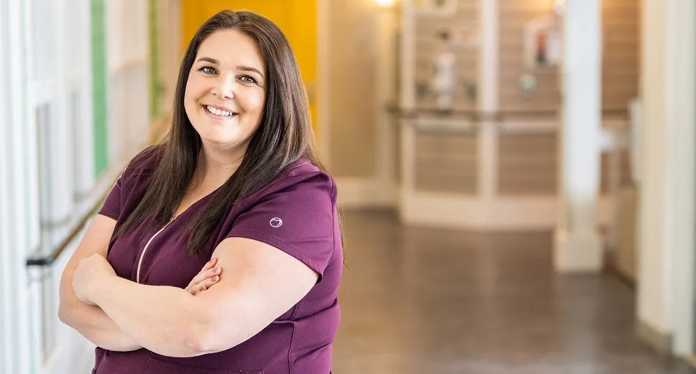 PEI resident care worker in scrubs standing in hallway