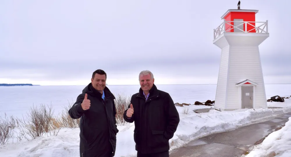 Two people standing shoulder to shoulder on a wharf