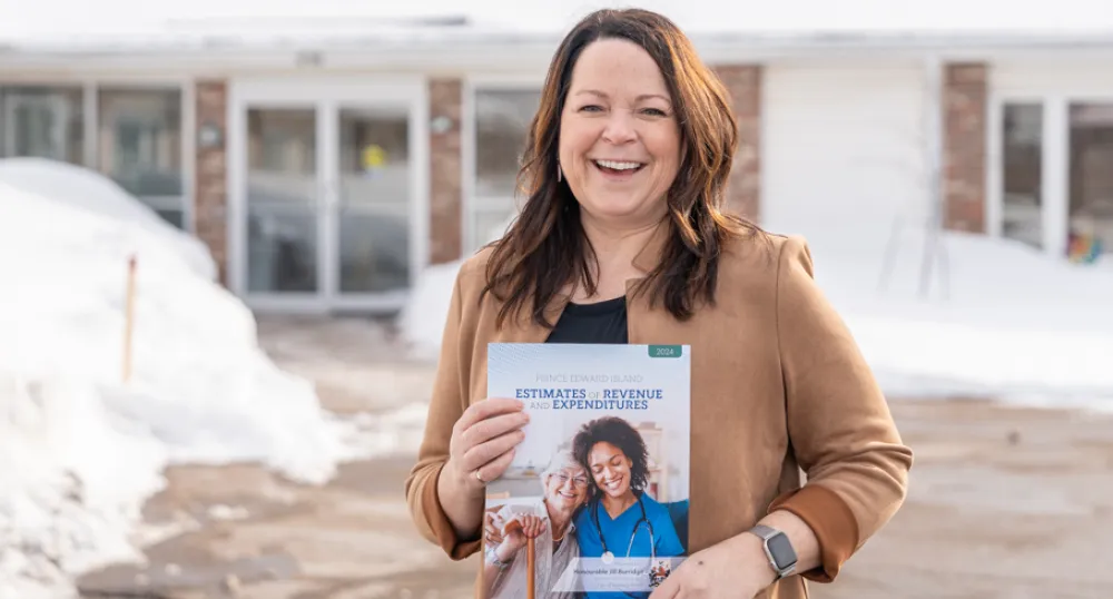 image of a person outside of a building holding a document in front of her