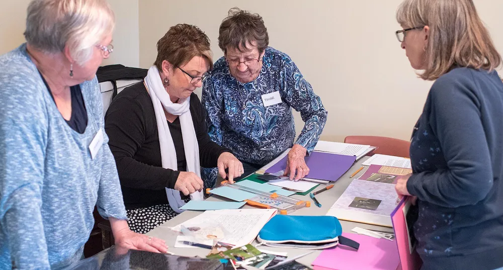 Applications being accepted for Seniors’ Secretariat grants Four people at a table working on scrapbooks