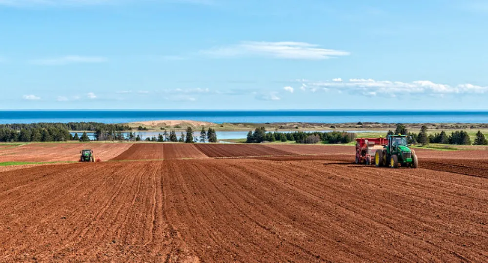image of two tractors plowing a field