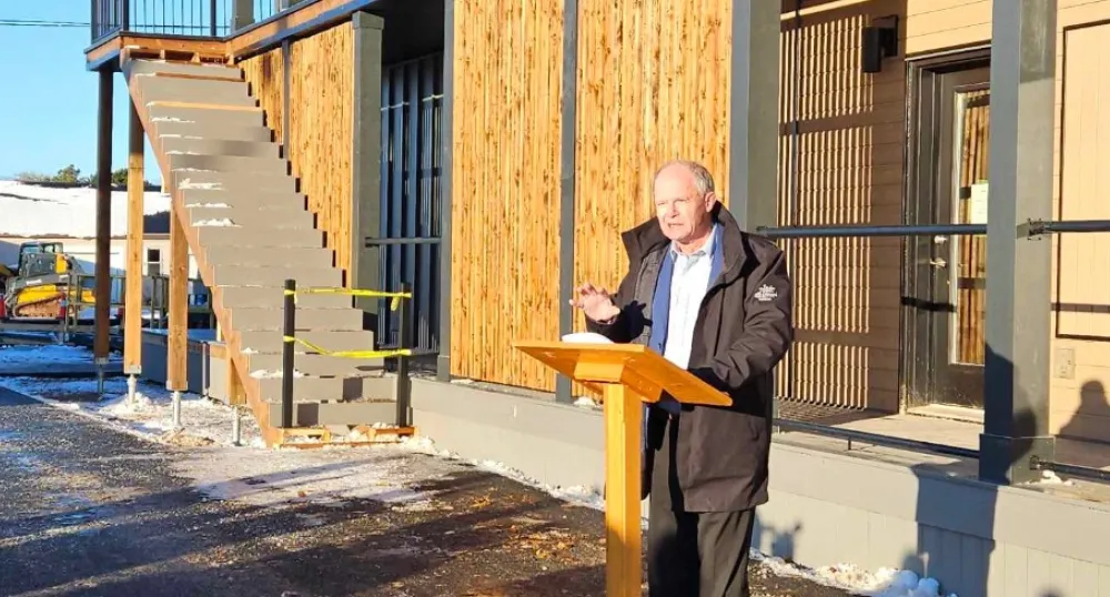 New housing in Alberton supports people with mental health, addictions image of a person speaking at a podium outside a building