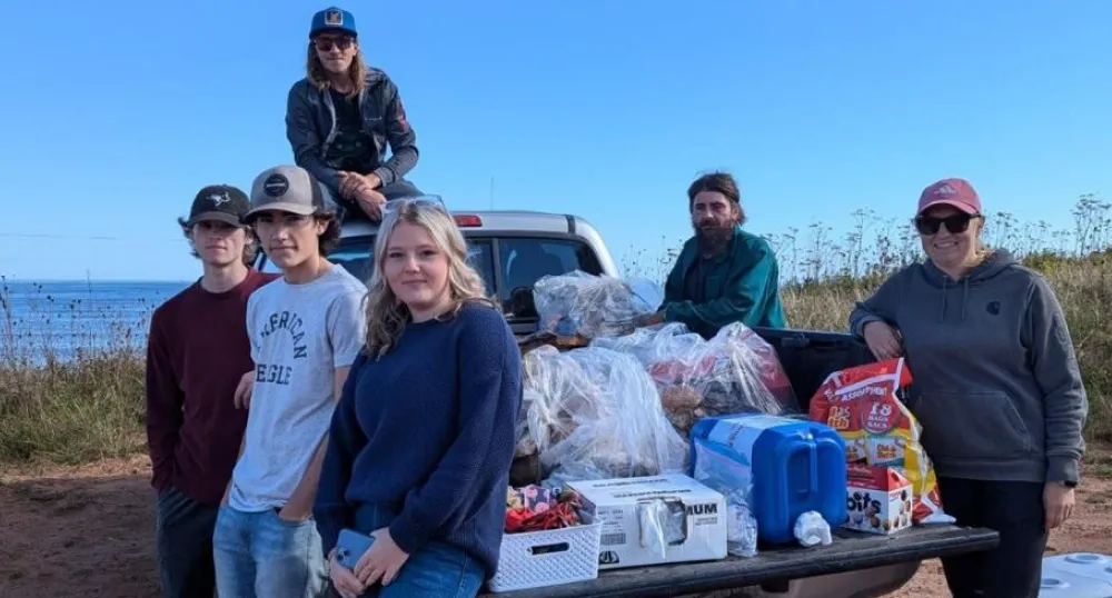 image d&#039;un groupe de personnes assises et debout autour d&#039;un camion garé près du rivage
