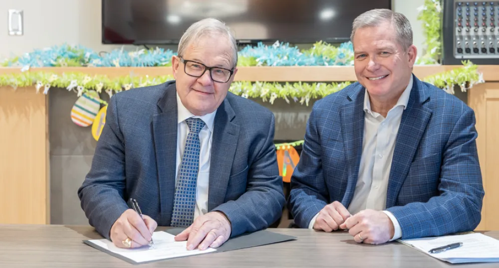 Lawrence MacAulay and Mark McLane sit at a table smiling at the camera.