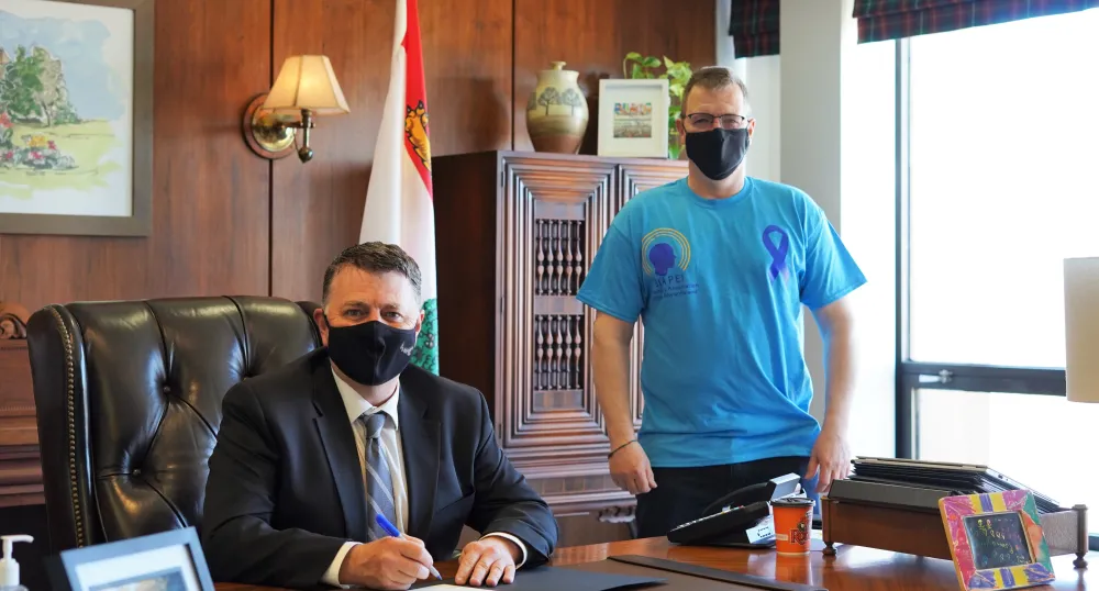 Statement by Premier Dennis King on Brain Injury Awareness Month Image of two people behind a desk