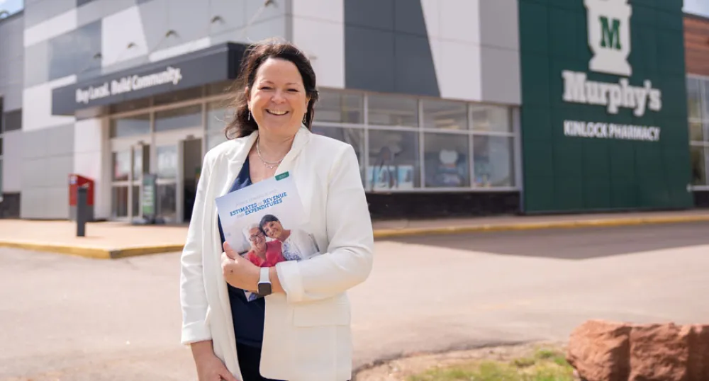 Budget presents plan to support and improve the lives of Islanders image of a person standing in front of a pharmacy while holding budget document
