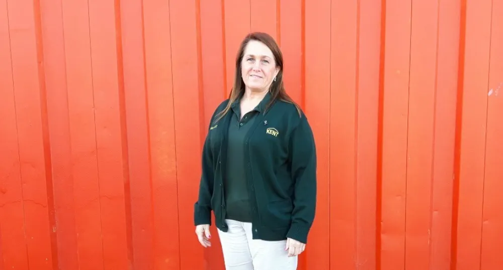 Candace Cormier stands outside against the backdrop of an orange building. 