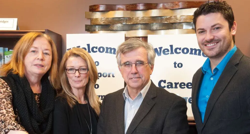 SkillsPEI connects new, former residents to Island workforce Minister Brown and three other people standing in front of Career Bridges sign and three of them are holding an information brochure.