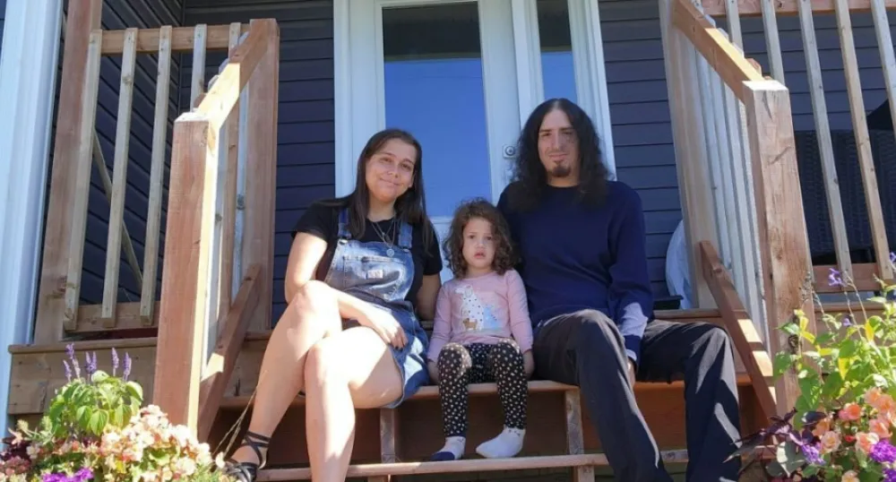 image of two adults and a child sitting on the stairs of a porch in front of a house