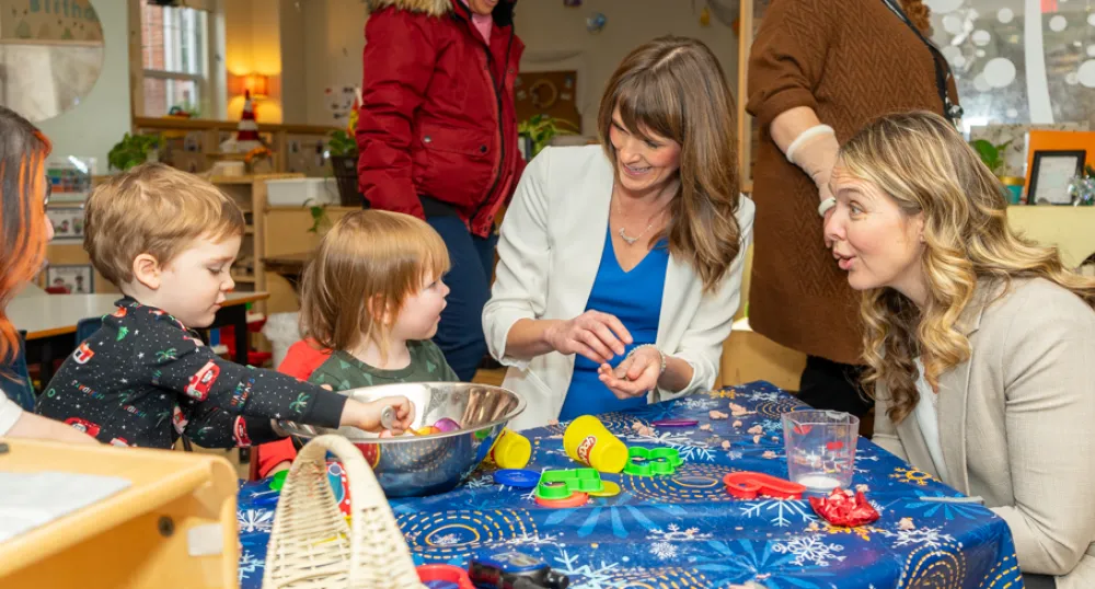 image of  some women sitting at a small table with some young children doing crafts