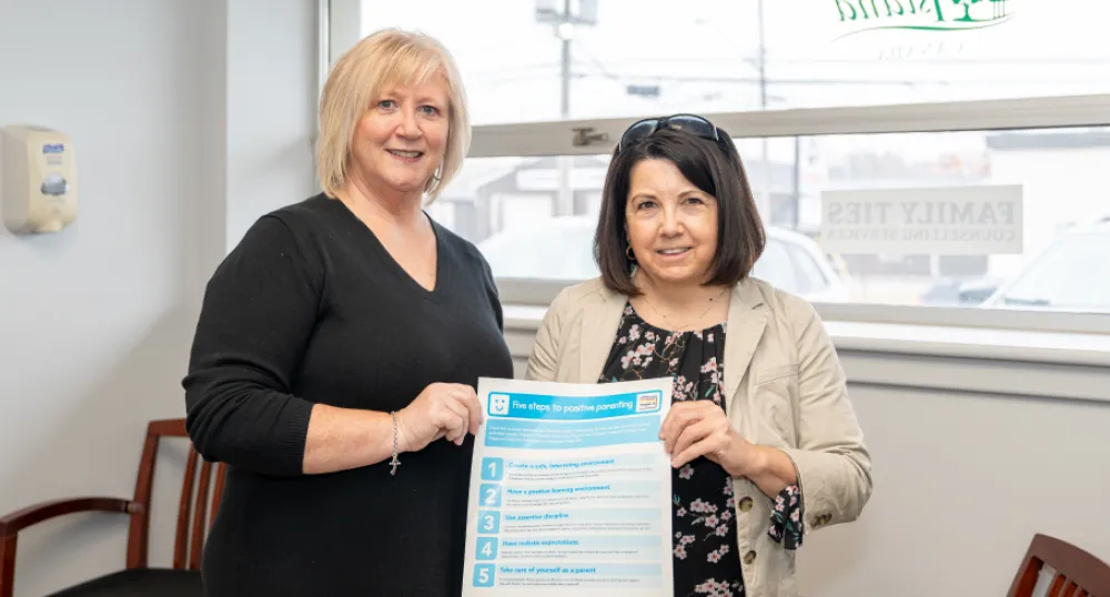 Positive Parenting: the Triple P approach image of two people in a room holding a small banner