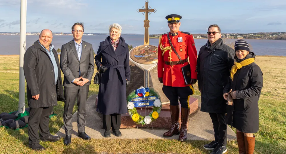 six people stand at the Acadian memorial at Skmaqn–Port-la-Joye–Fort Amherst National Historic Site