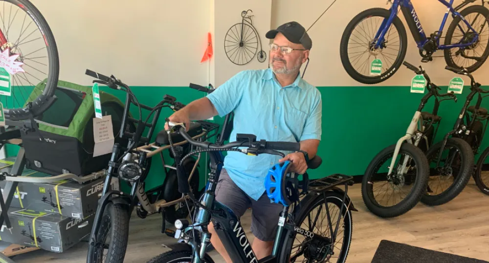 e-bikes catching on in PEI thanks to participating retailers, provincial rebate image of a person inside a room, holding an electric bike with others in the background