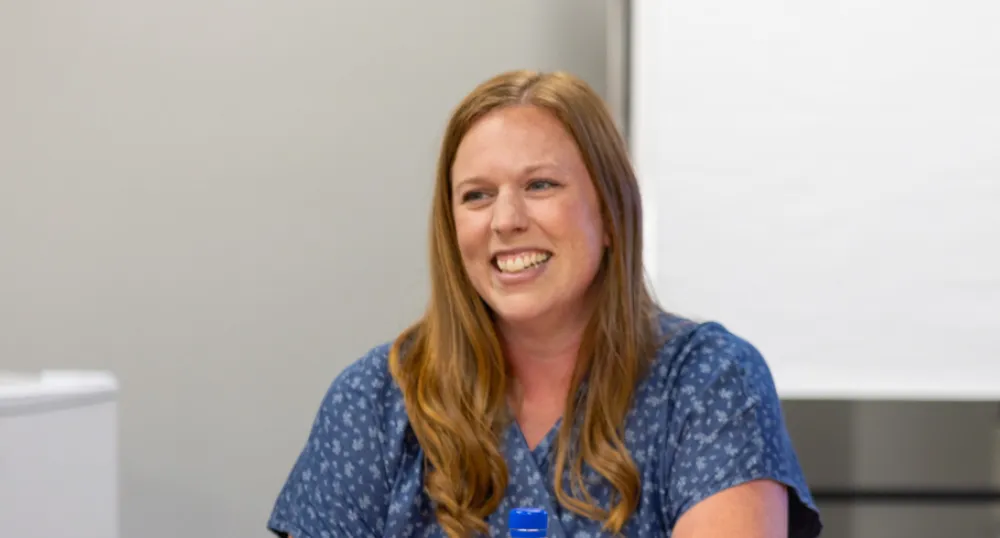 image of a person at a meeting table smiling