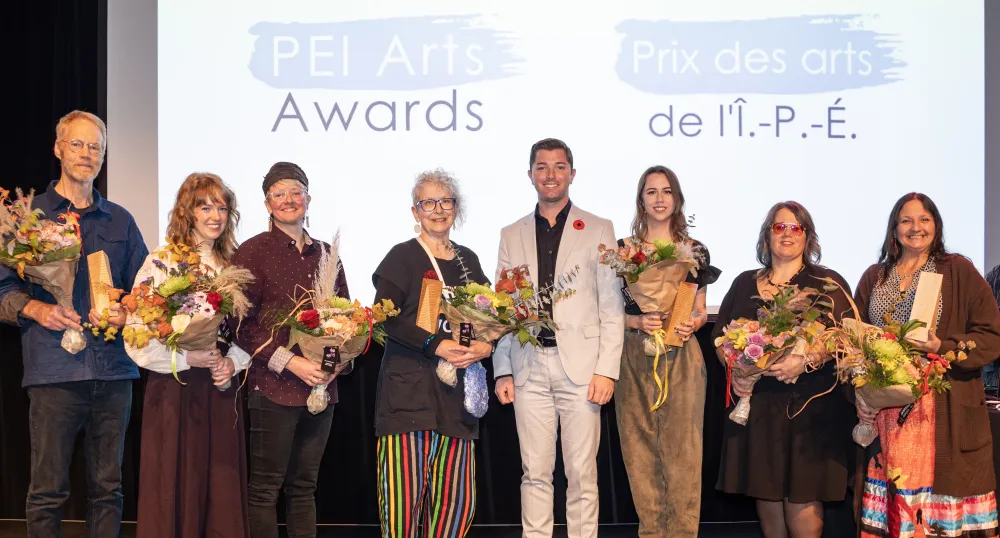 image of a line of people standing on a stage holding bouquets of flowers receiving awards