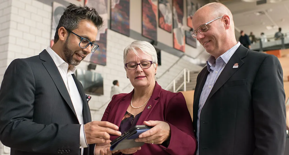 Online tool will help Islanders reduce energy costs Photo shows three people looking at an app on a tablet