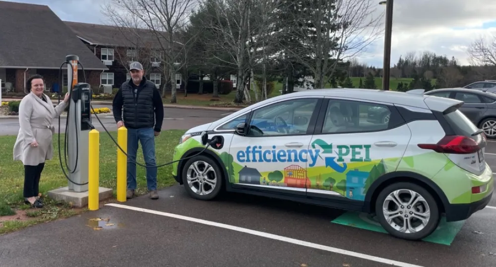two people standing by the electric charger while charging their car