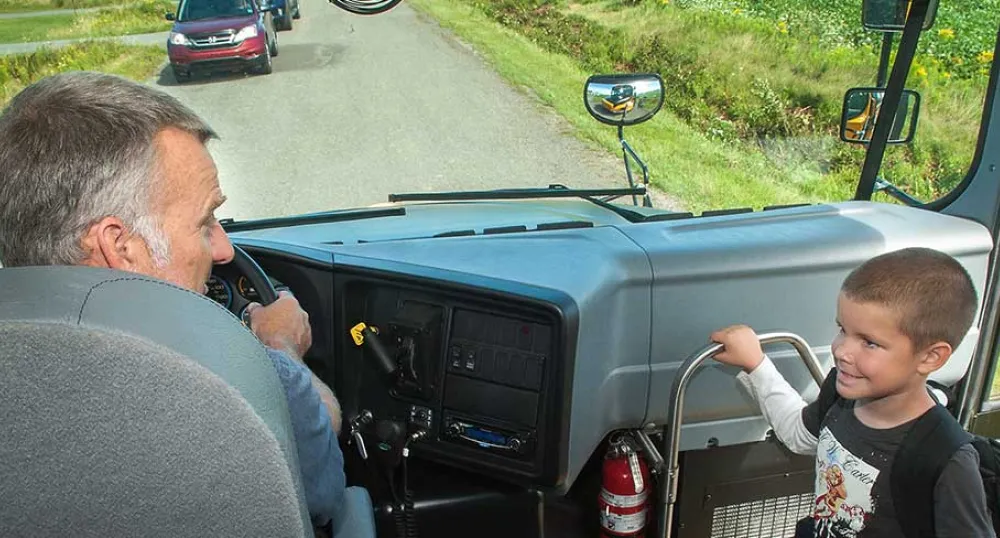 Bus driver greets child as he loads the school bus