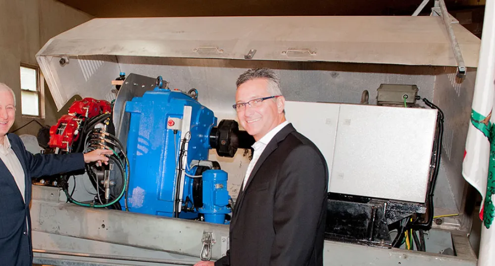 Frontier Power Systems expanding to Georgetown Minister MacDonald and Carl Brothers stand in front of wind trubine machinery under production.