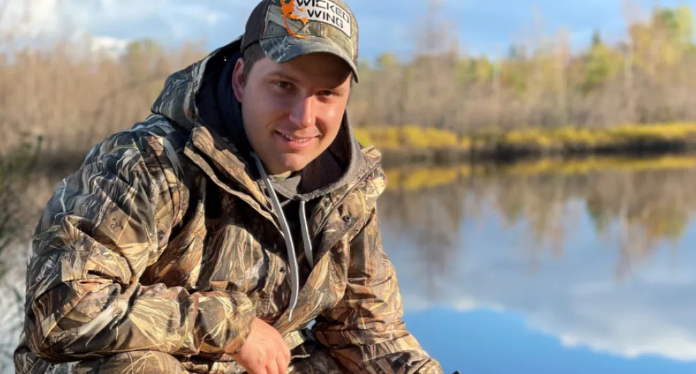 image of a person in hunting gear with a pond in the background