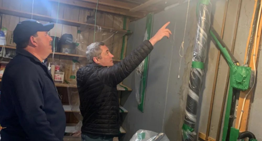 Photo shows a man installing insulation in a home