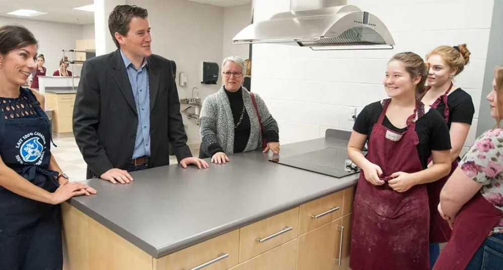 Photo shows ministers speaking with students in the newly renovated culinary arts kitchen.