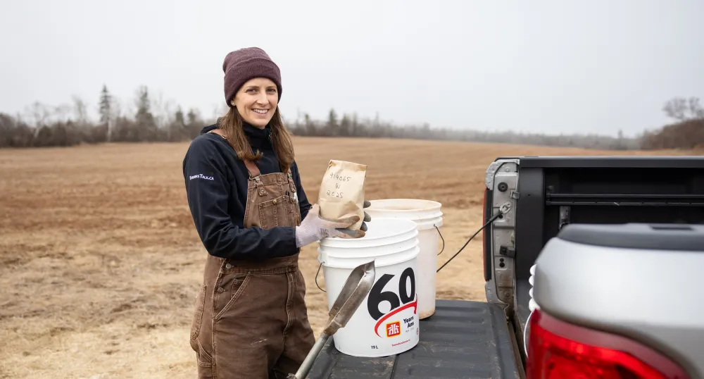 Kyra Stiles holds a paper bag of soil next to a truck