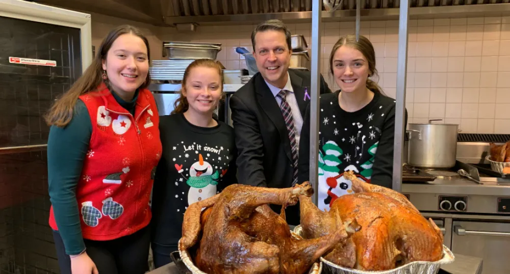 New school food program coming in January Four people standing in a kitchen behind two cooked turkeys