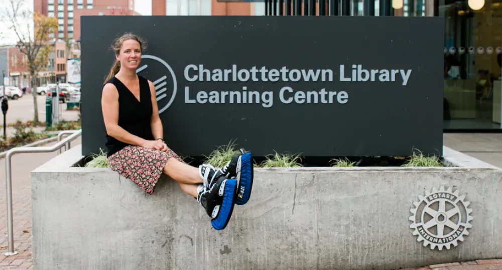 Island residents can borrow hockey skates with their public library card image of a person wearing ice skates and sitting bedside a sign outside a library