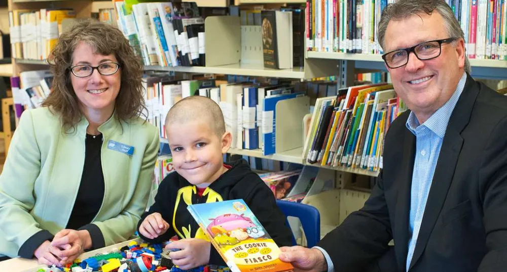 A man and woman with a school aged child holding a book