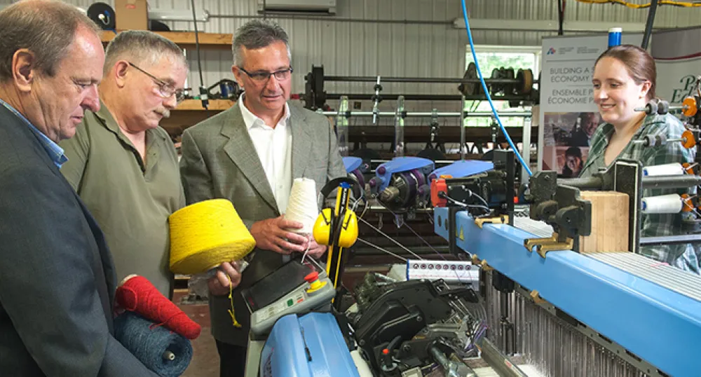 MacAusland's Woolen Mills Equipment upgrades Four people looking at loom machine