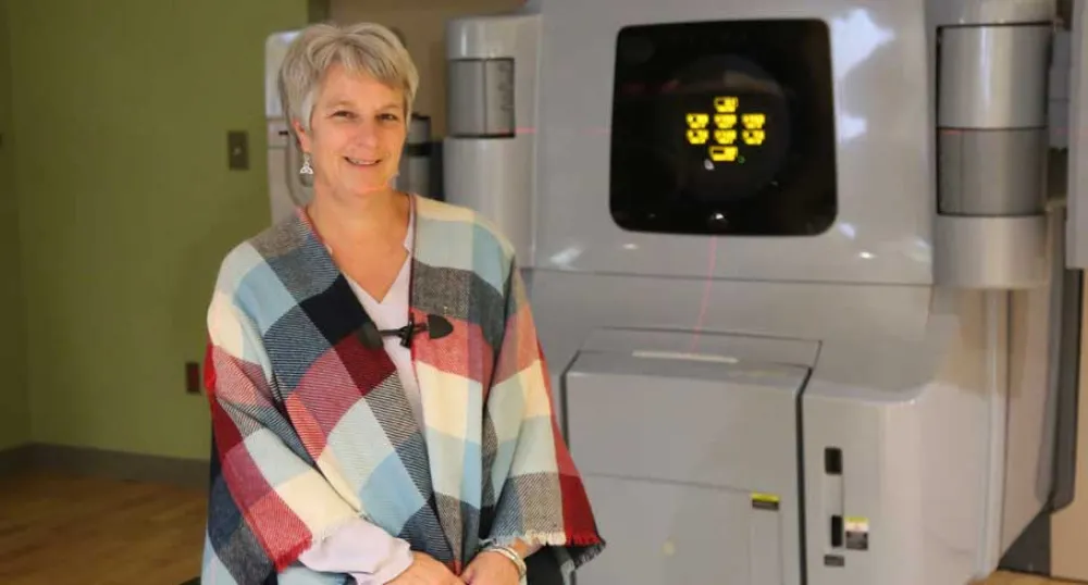 Dawn MacIsaac sits by one of the older Linear Accelerator&#039;s at the PEI Cancer Treatment Center