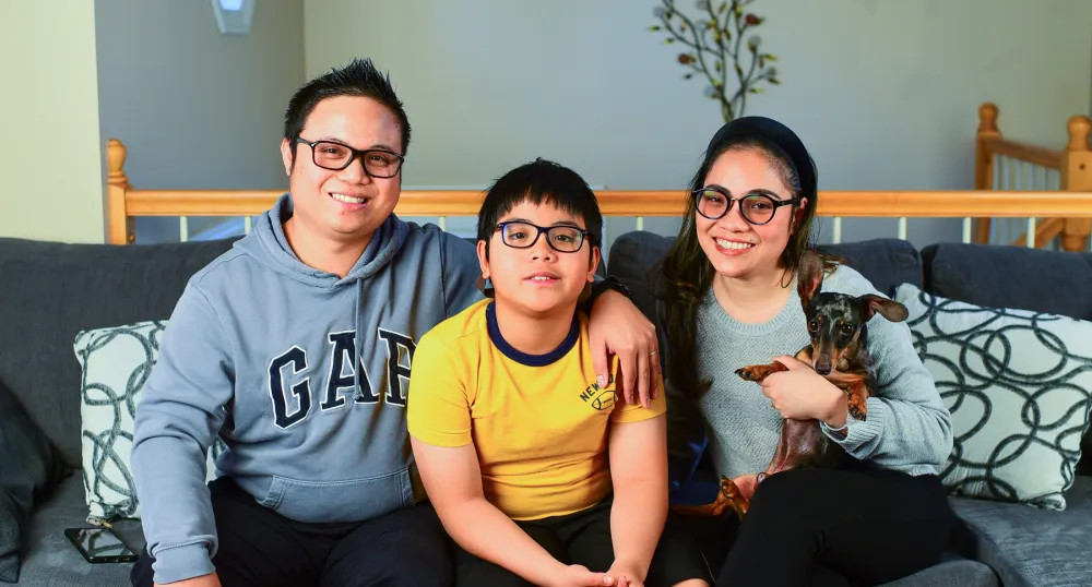 Woman and man posing with their son and dog on a couch