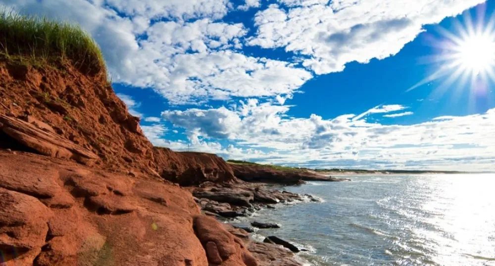 Scenic photo of PEI red cliffs and the ocean in the sun