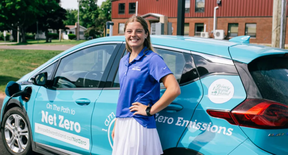 Molly Doyle, the Government of Prince Edward Island’s Net Zero Ambassador image of a person standing in front of an electric vehicle