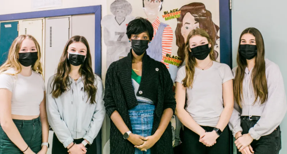 Woman and four girls standing outside of a classroom
