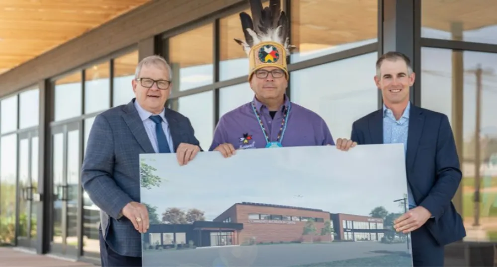 image of three people in front of a building holding architectural rendering of a building