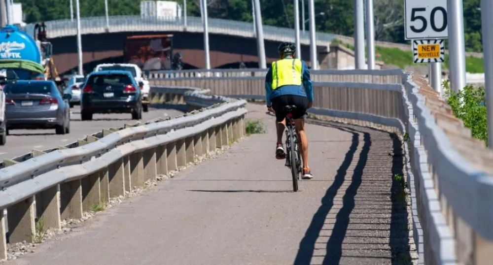 Person biking over a bridge, while wearing a helmet