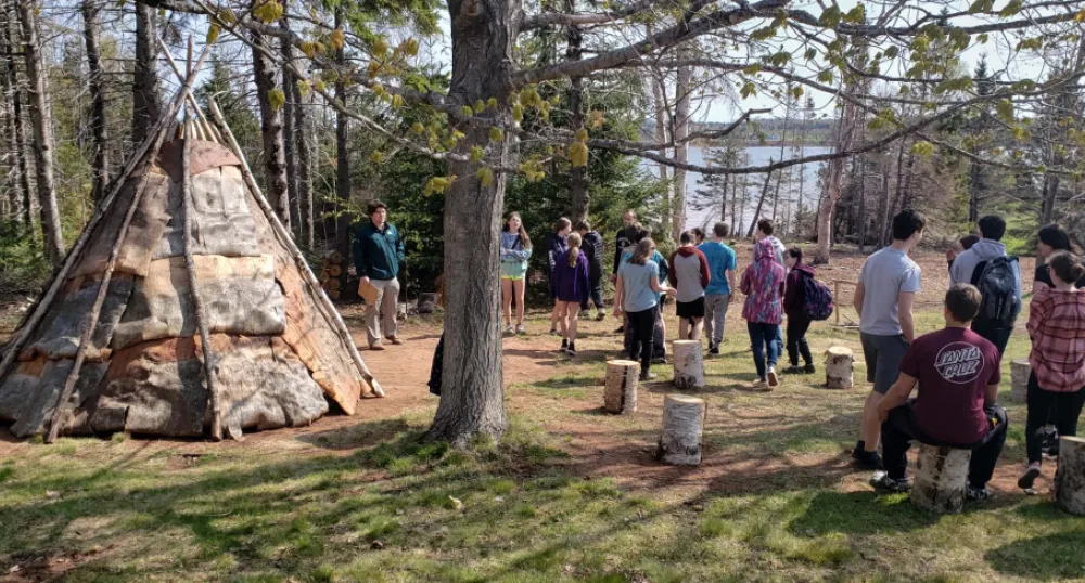 image of a group of students in the woods near a teepee